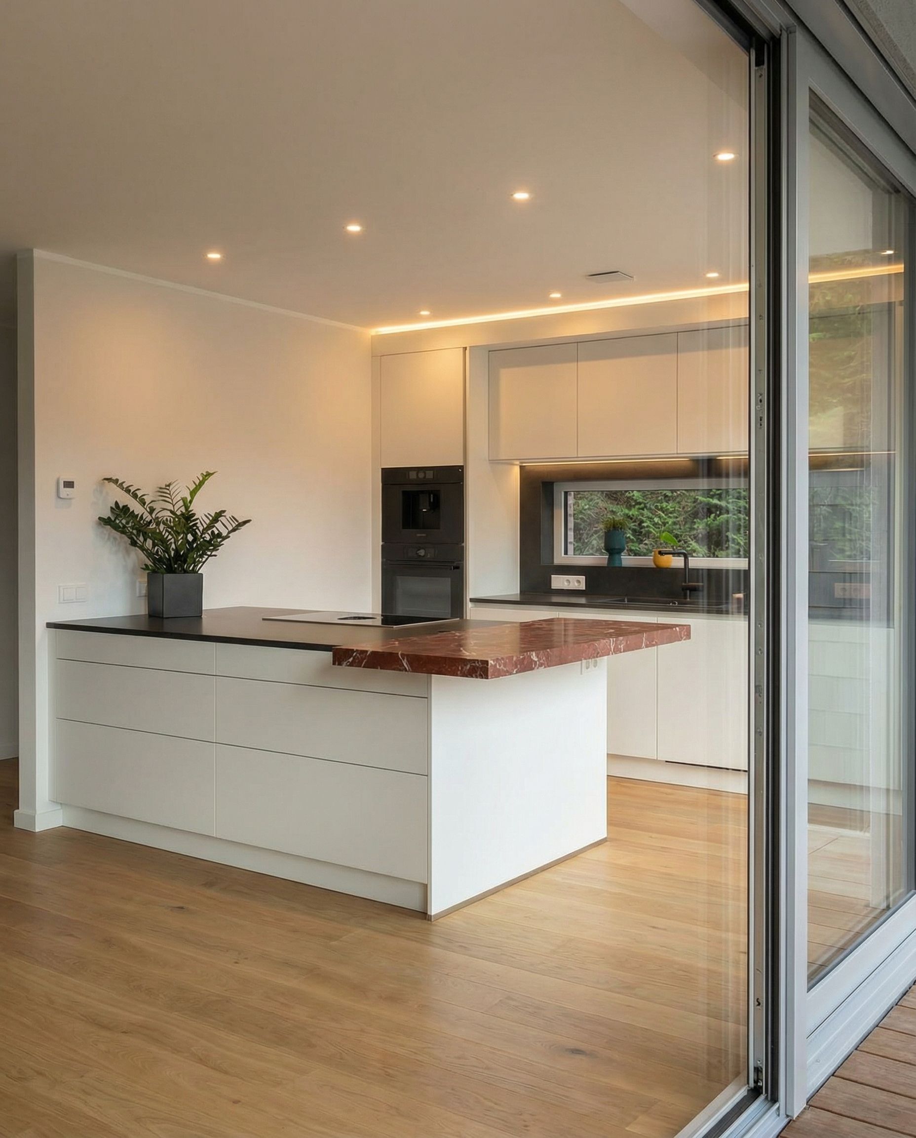 Kücheninsel und Raumreflexion in der großen Glasschiebetür zur Terrasse.